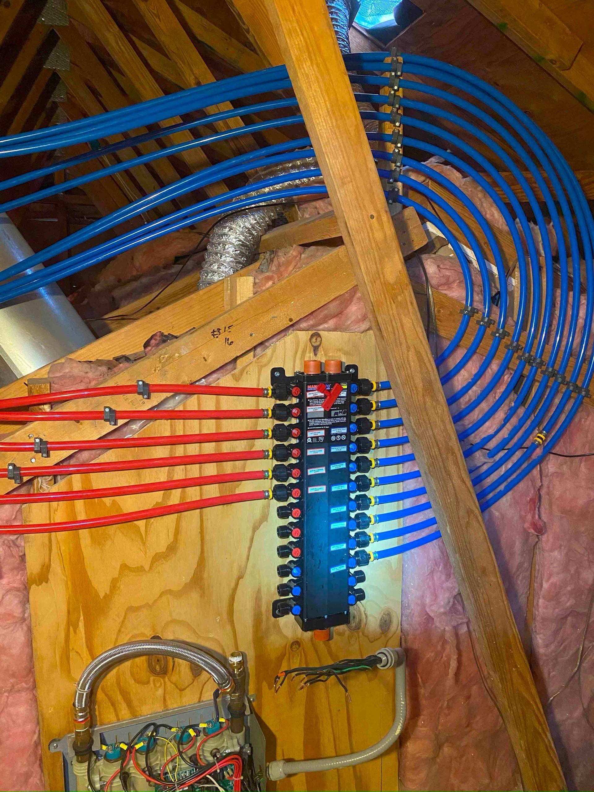A bunch of wires are connected to a wooden box in the attic.