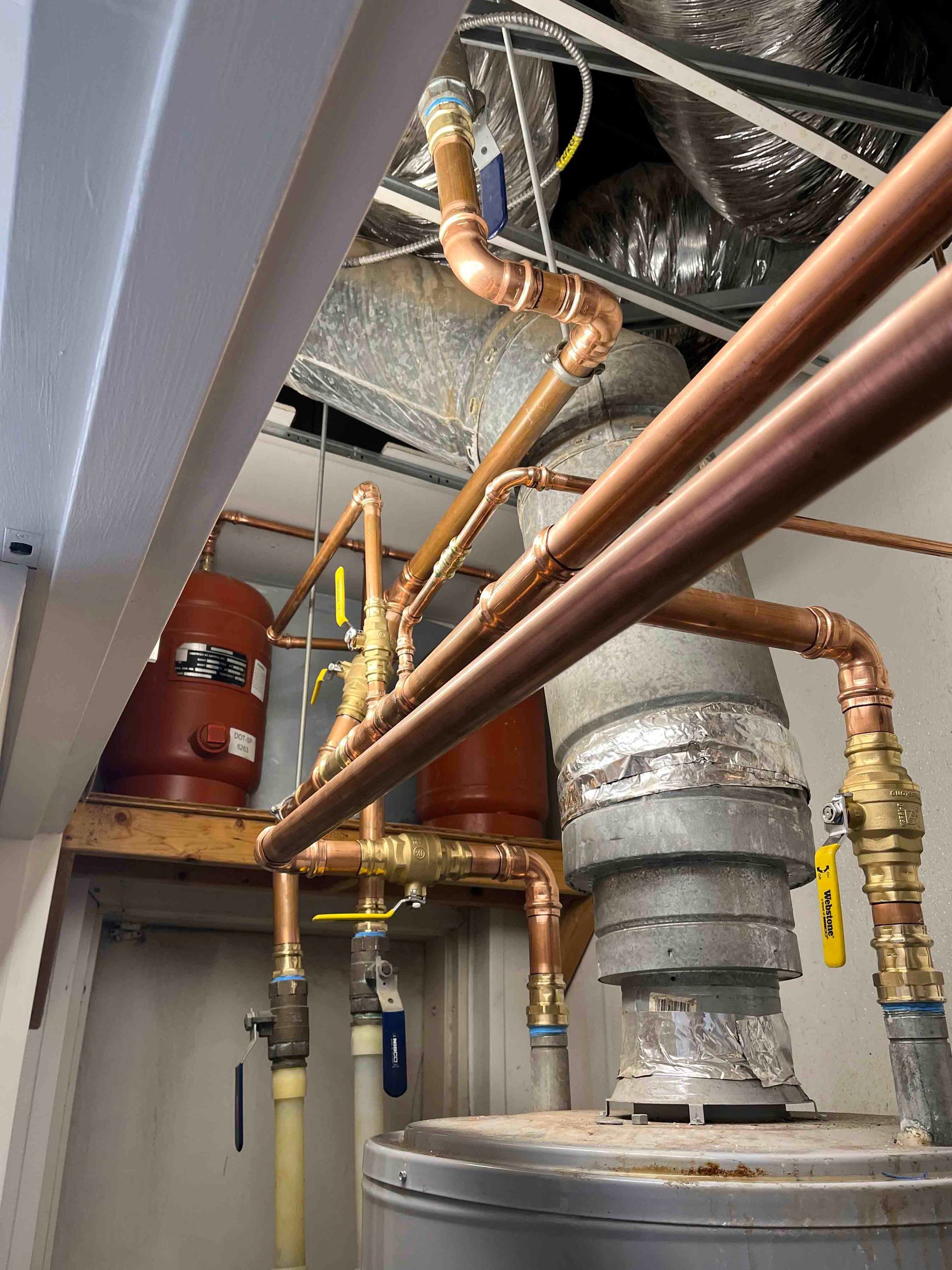 A room with a lot of pipes and a water heater