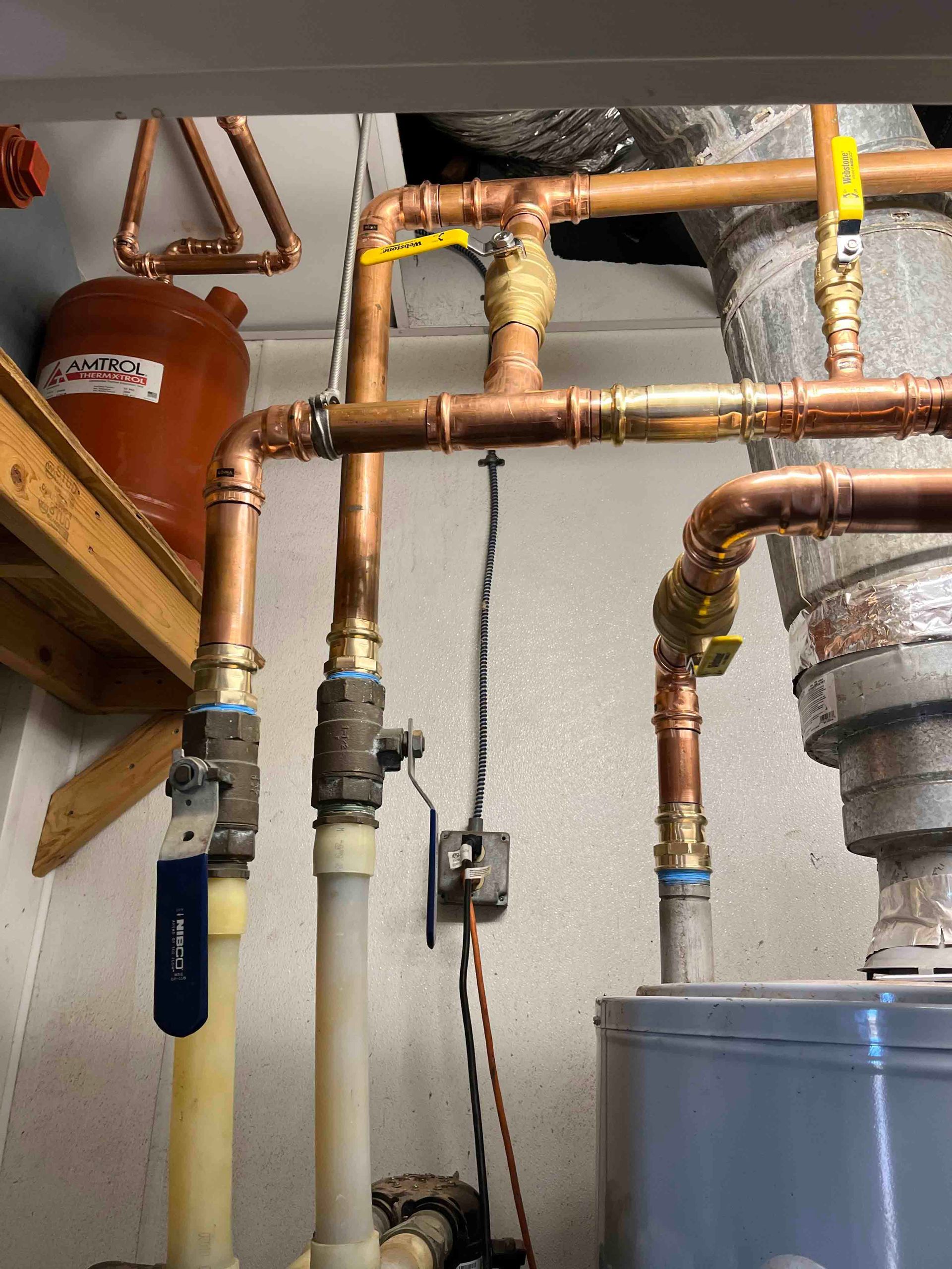 A room with copper pipes and a water heater