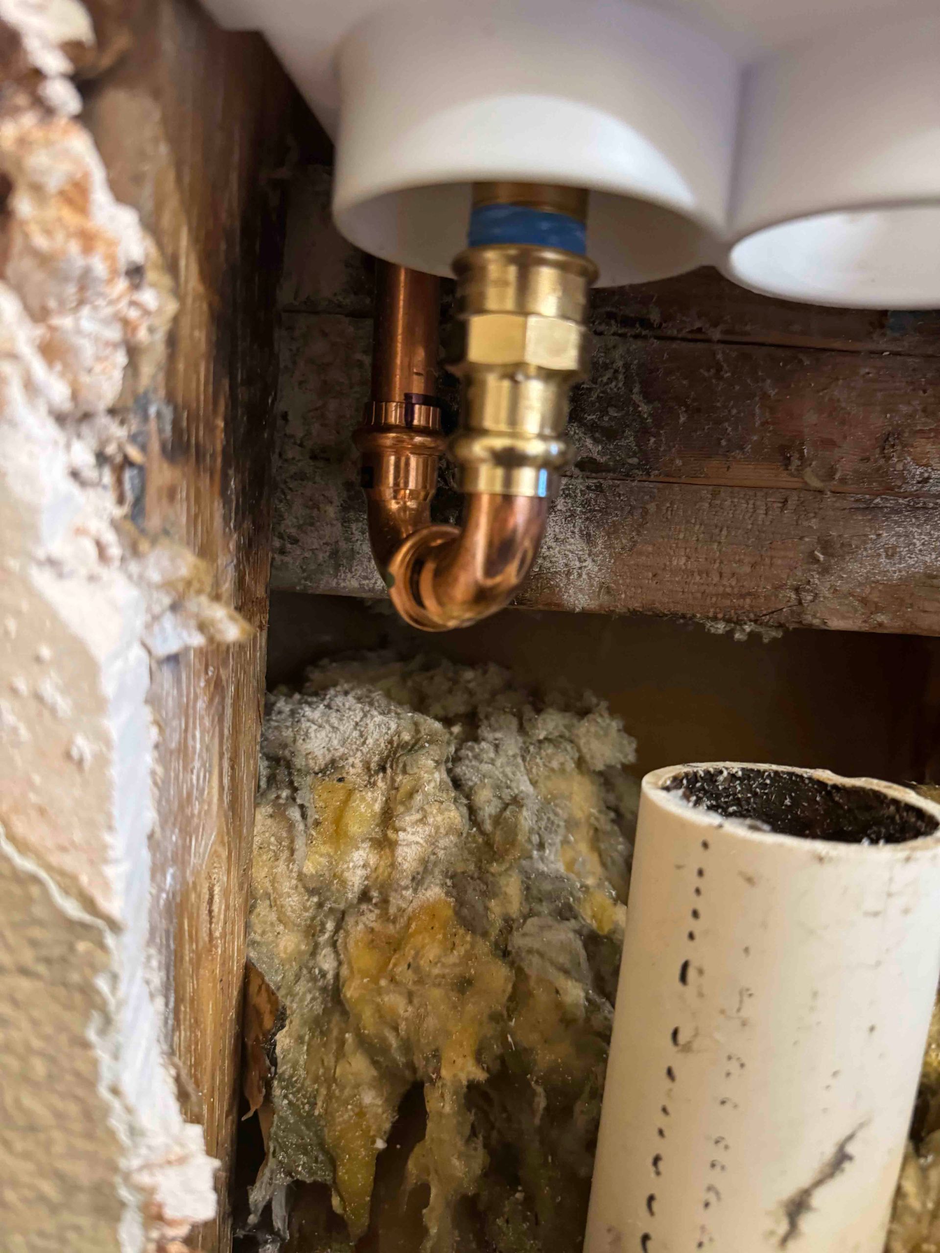 A copper pipe is coming out of a hole in a wall