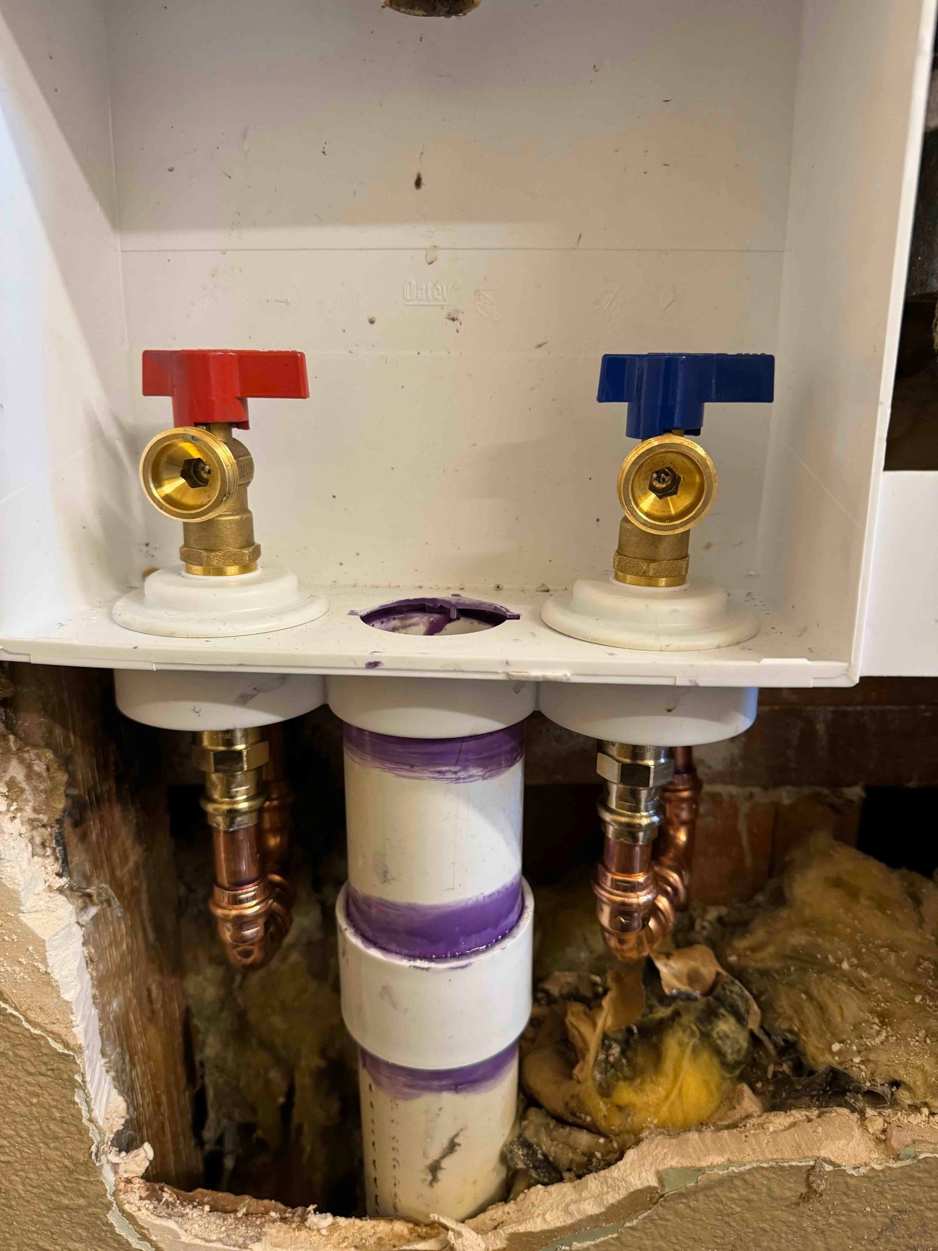 A close up of a washer and dryer valve in a wall.