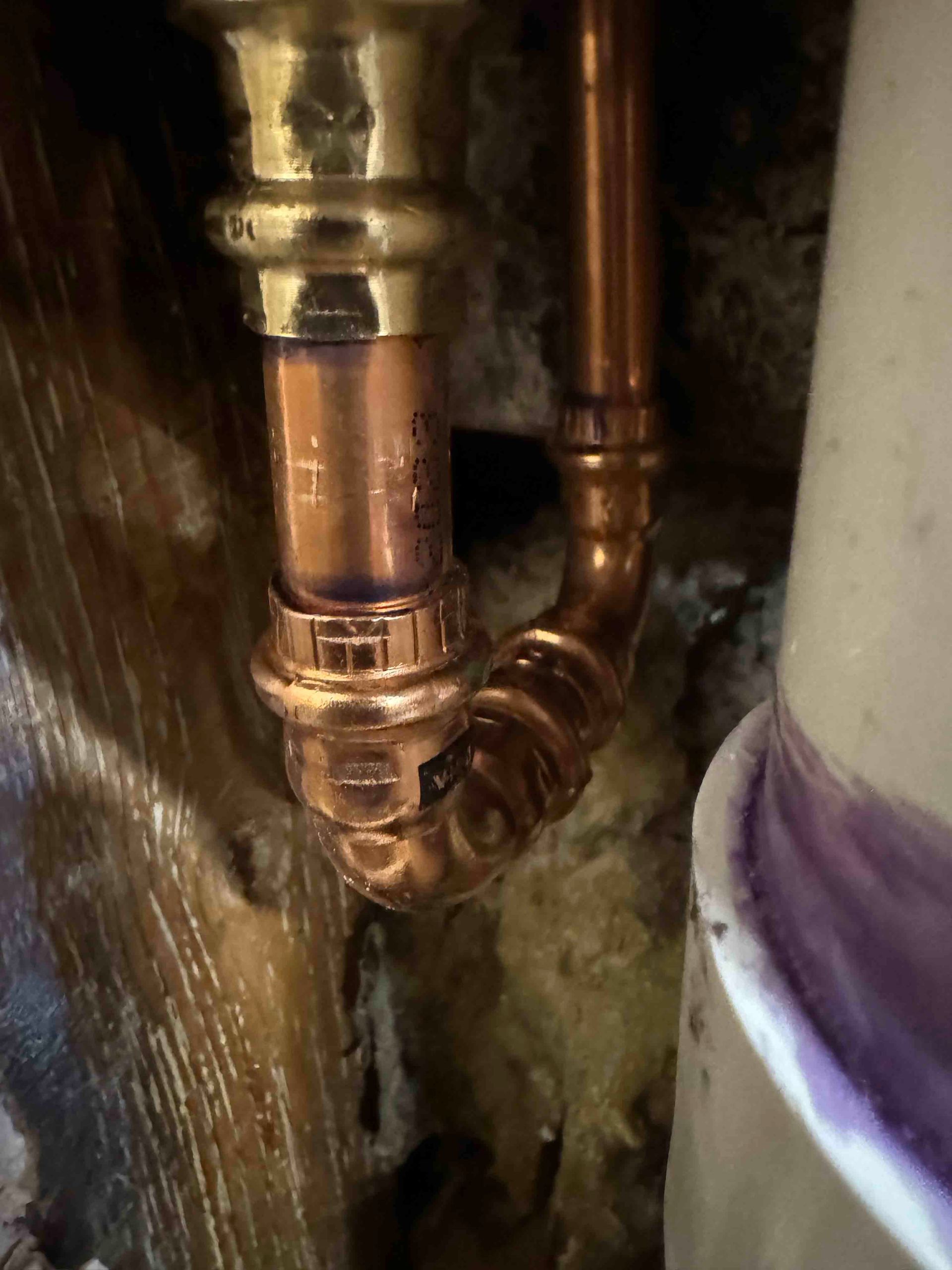 A close up of a copper pipe connected to a pipe.