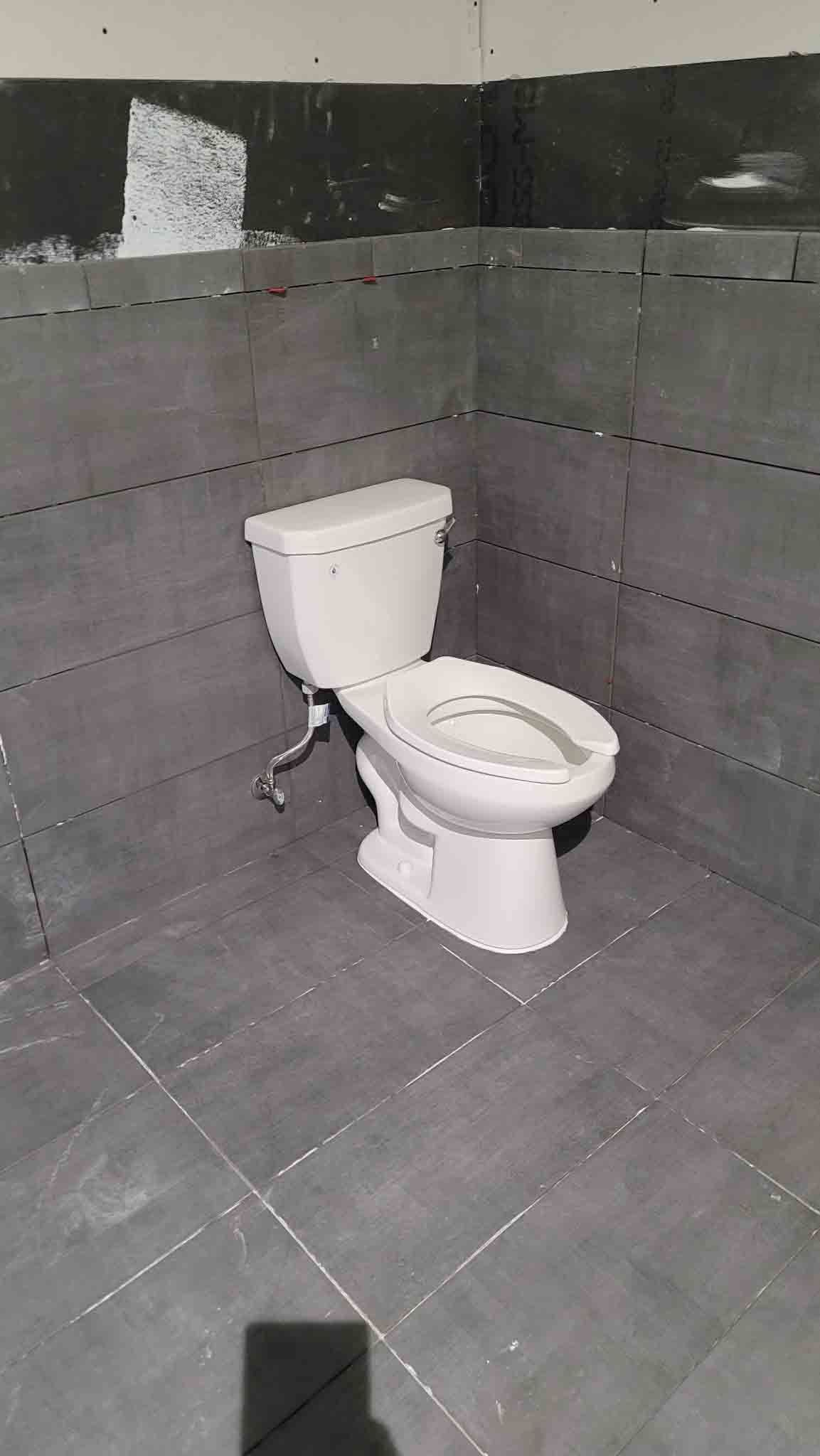A toilet is sitting in a corner of a bathroom.