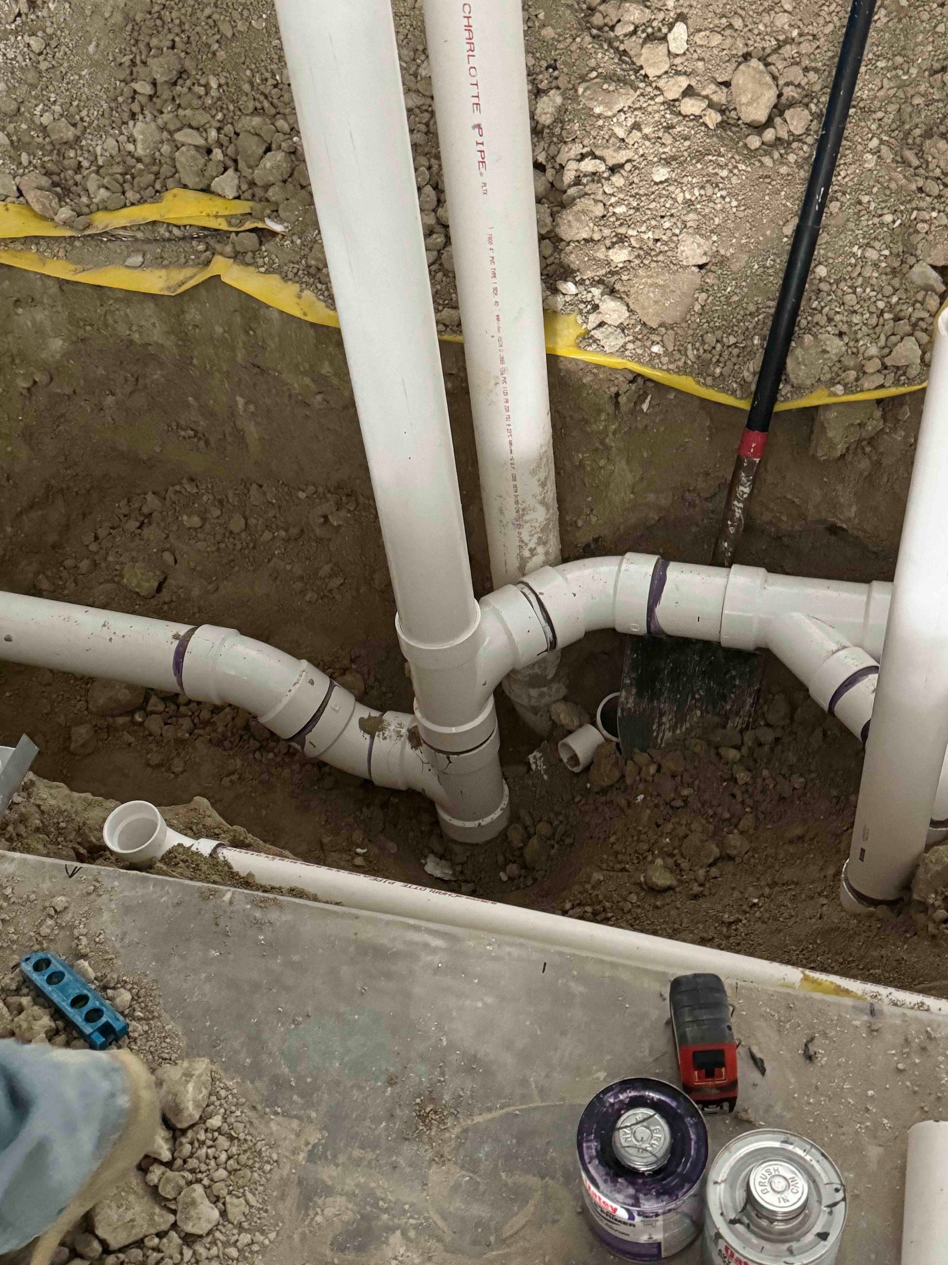 A person is working on a drain pipe in the dirt.