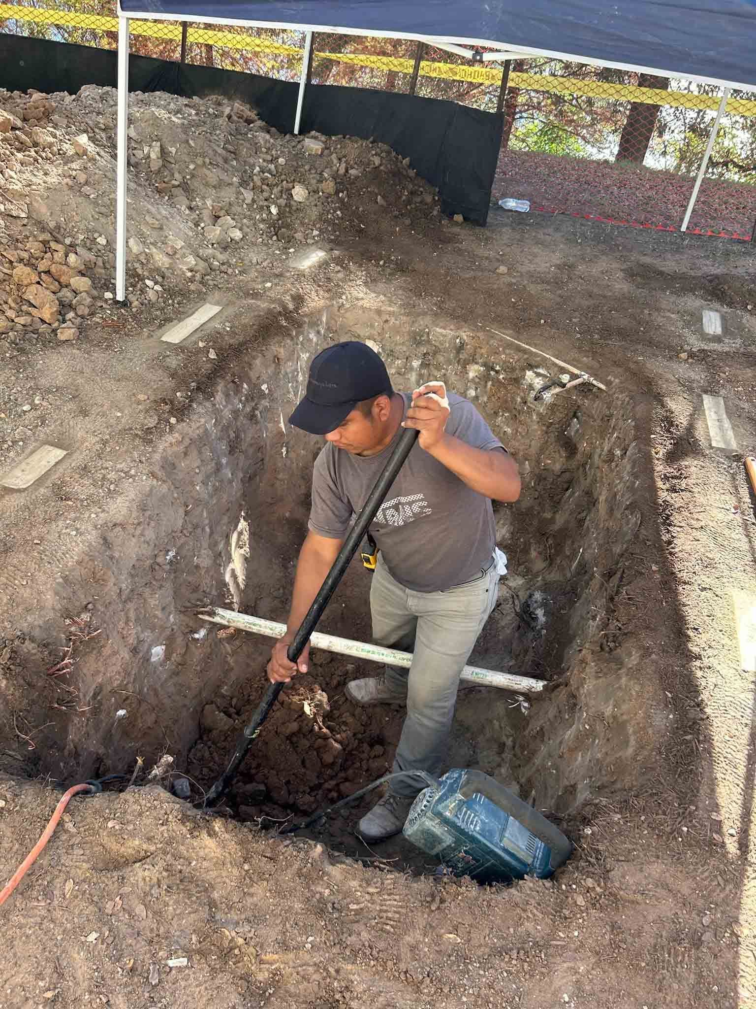 A man is digging a hole in the ground with a shovel.