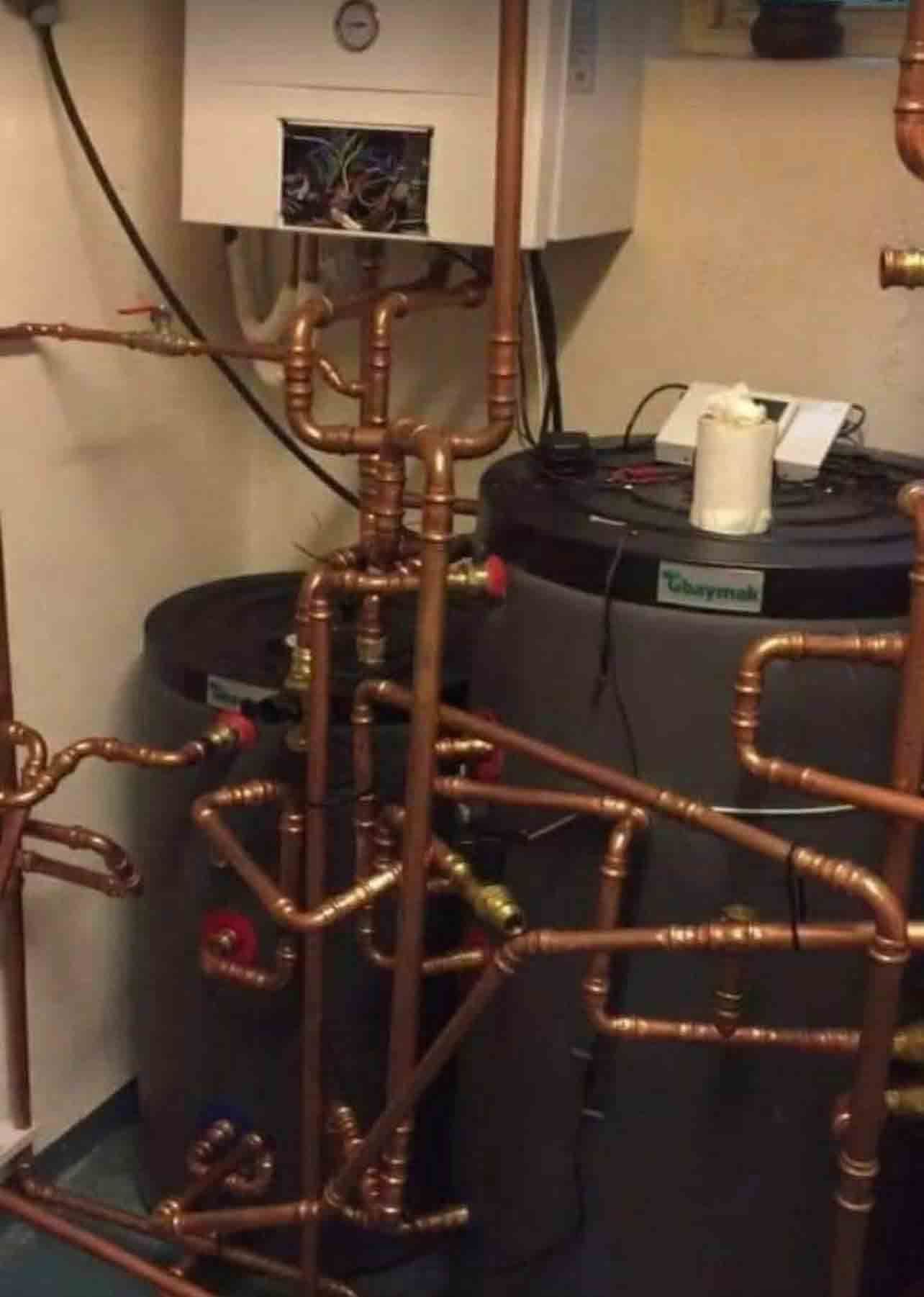 A water heater is surrounded by copper pipes in a room