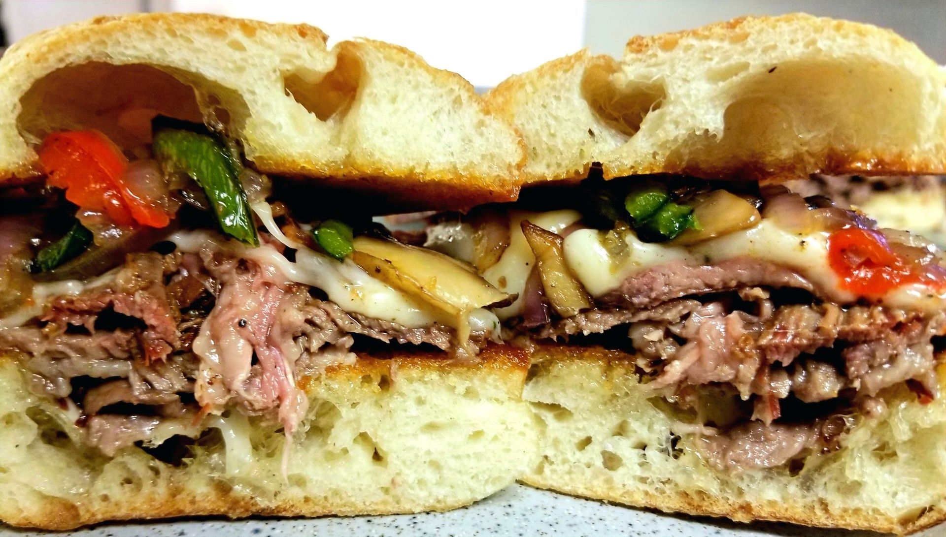 A sandwich with meat and vegetables is cut in half