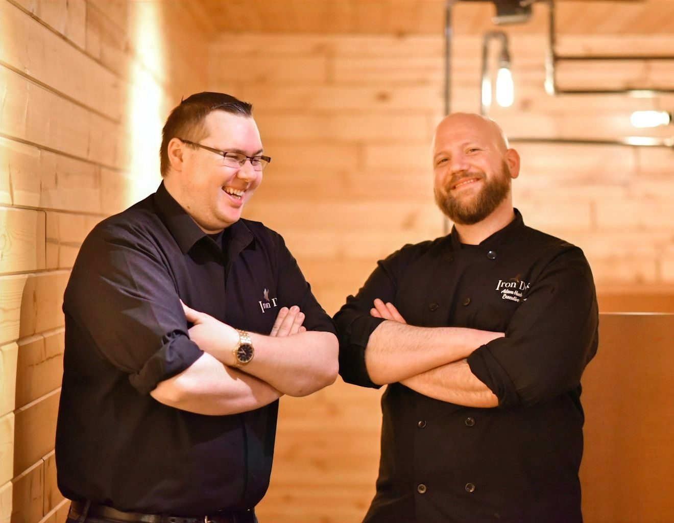 Two men are standing next to each other with their arms crossed.
