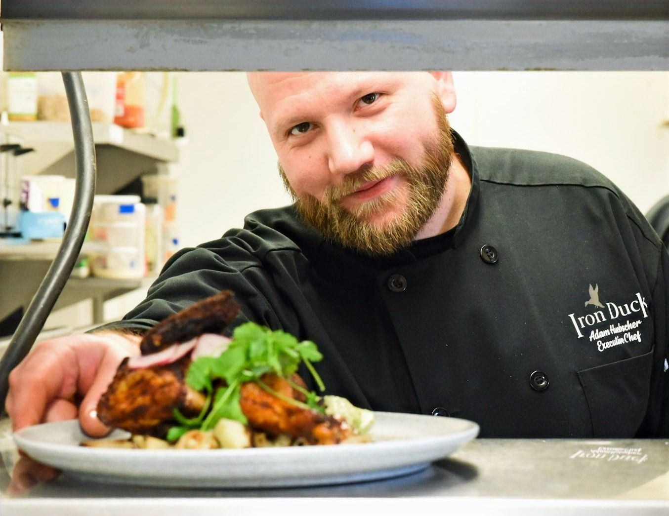 A man in a chef 's uniform is holding a plate of food