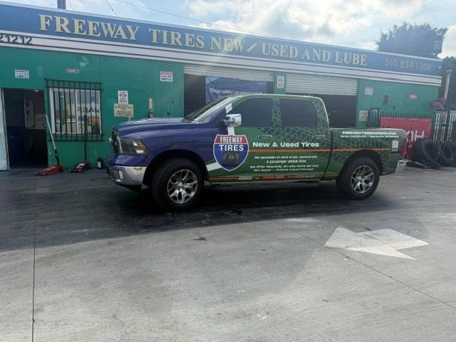 Blue pickup truck parked outside Freeway Tires storefront with “New & Used Tires” sign