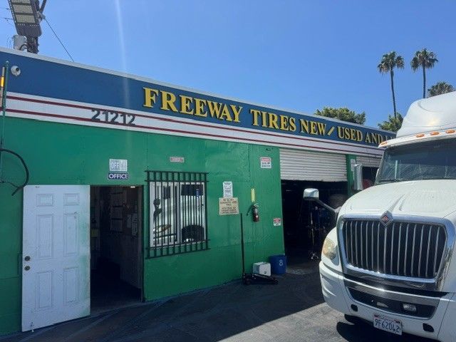 Freeway Tires store exterior with green facade and a white truck parked outside