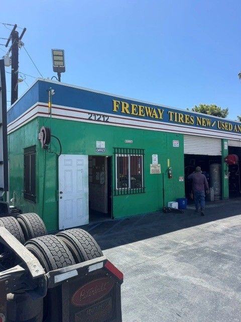 Freeway Tires shop exterior with green storefront, tire stacks, and a person near the entrance