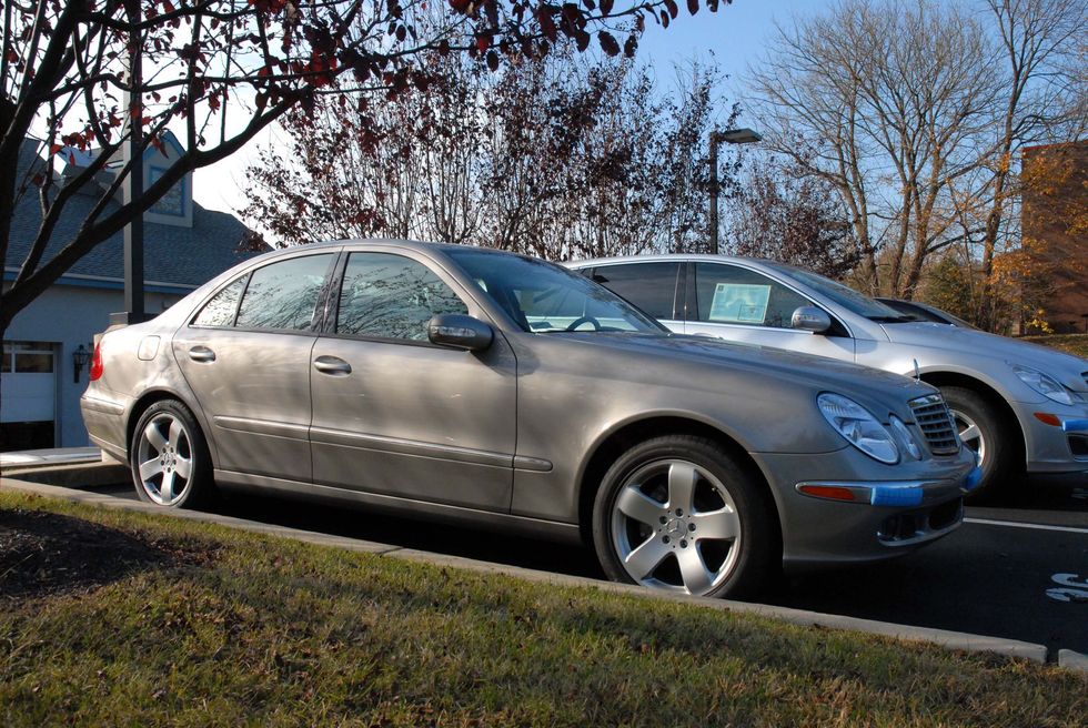 Silver sedan parked on a grassy curb beside another car on a sunny day