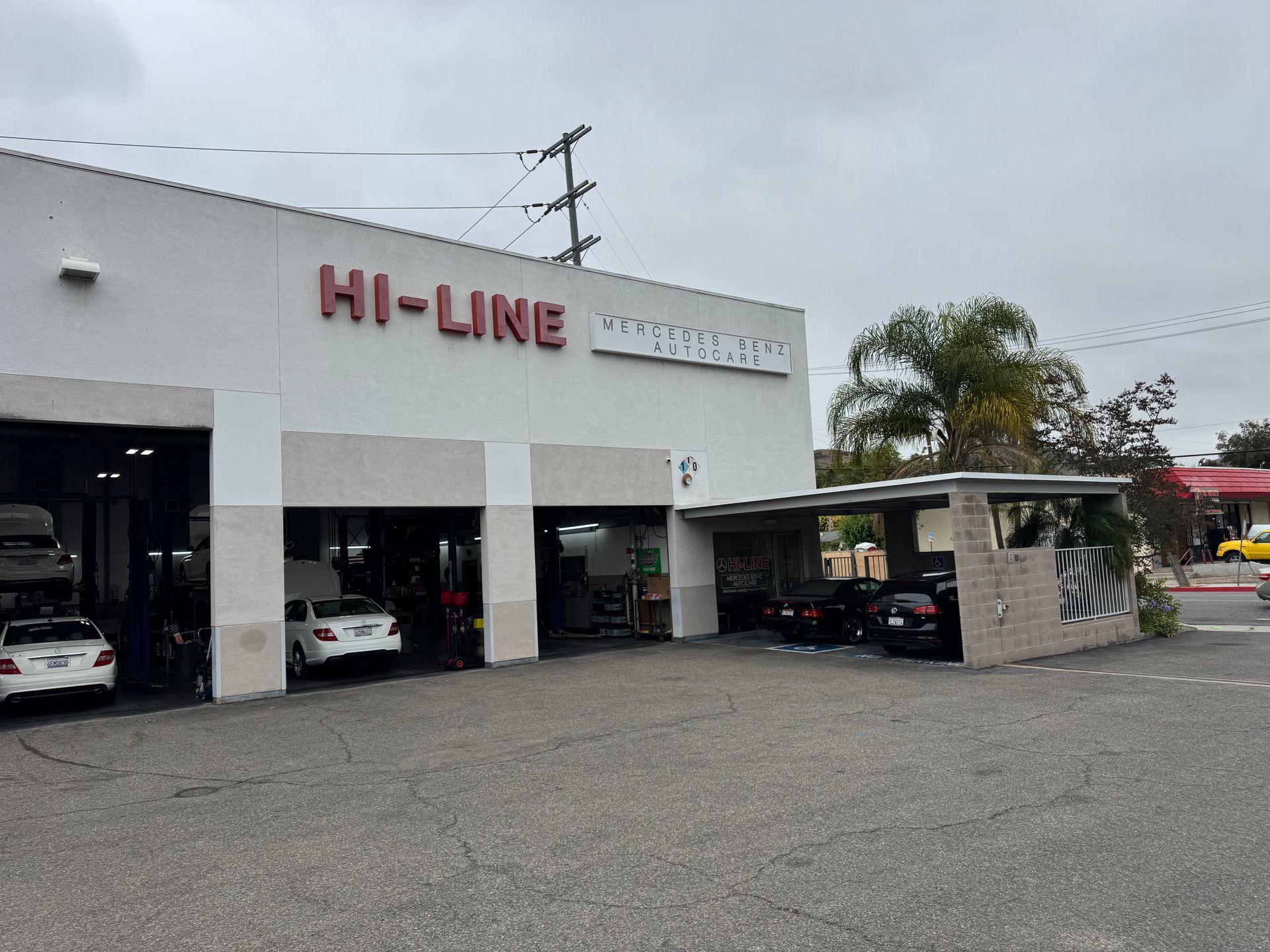 Hi-Line automotive shop exterior with white facade, open service bays, and parked cars