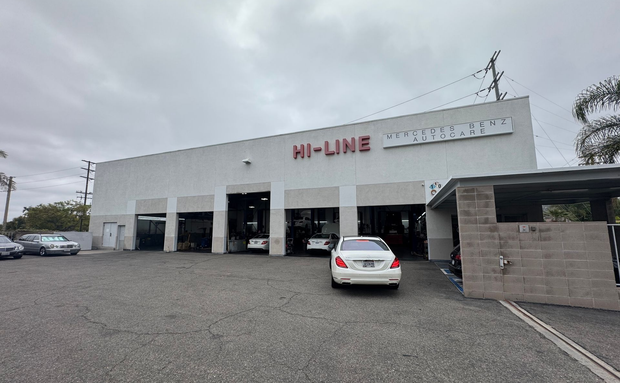 HI-LINE auto service building with a white car parked in front on a gravel lot under cloudy skies