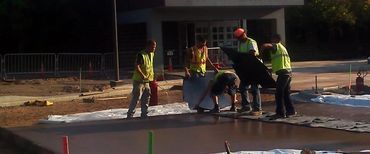 A group of construction workers are working on a concrete floor.
