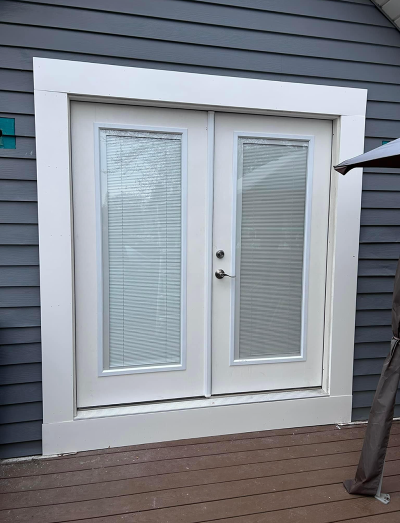 A white door with blinds on it is on the side of a house