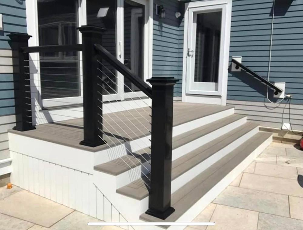 A deck with stairs and a black railing in front of a blue house