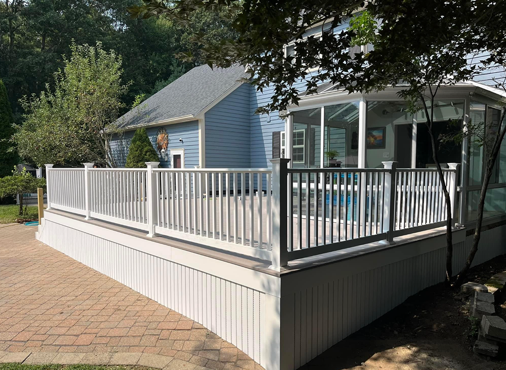 A blue house with a white deck and a screened in porch