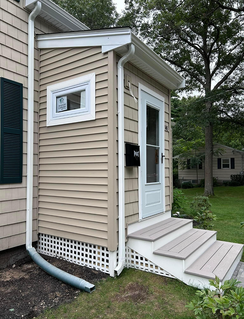 A small house with stairs and a mailbox on the side of it