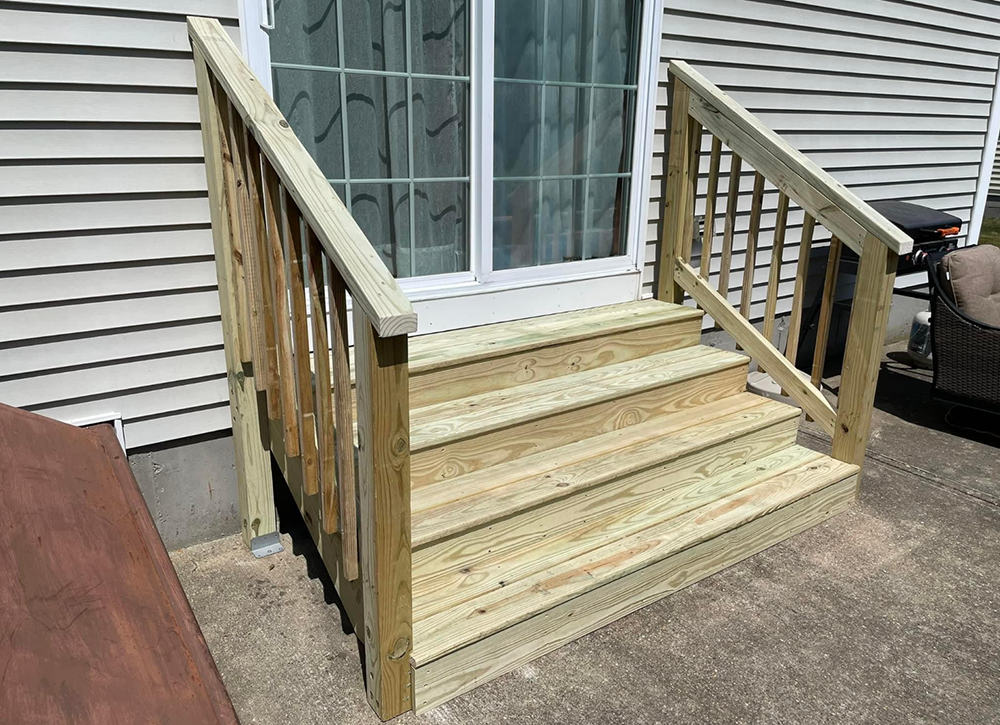 A wooden deck with stairs leading up to a sliding glass door