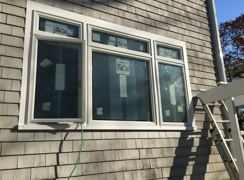 A ladder is sitting next to a window on the side of a house