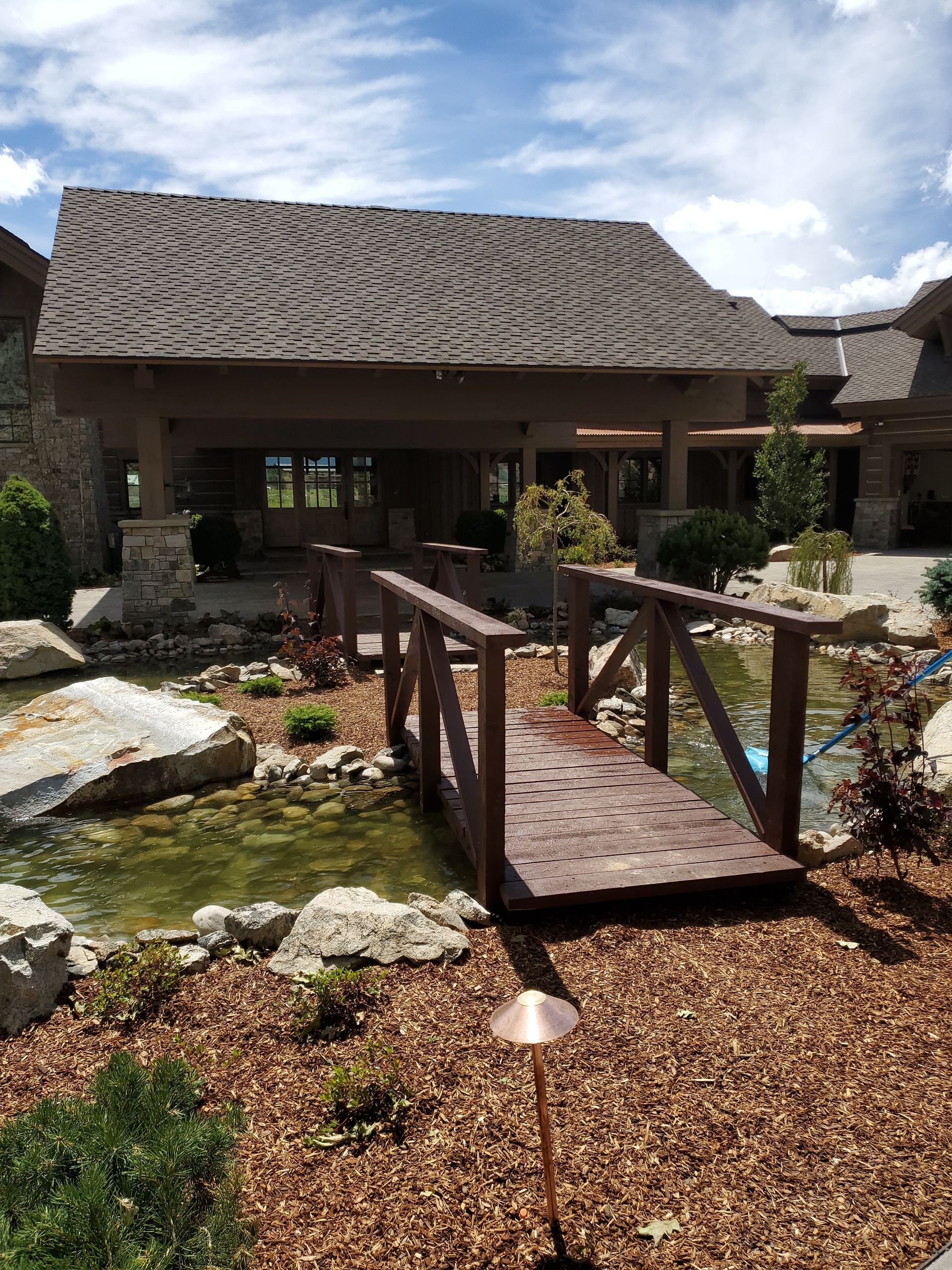 A wooden bridge over a pond in front of a house