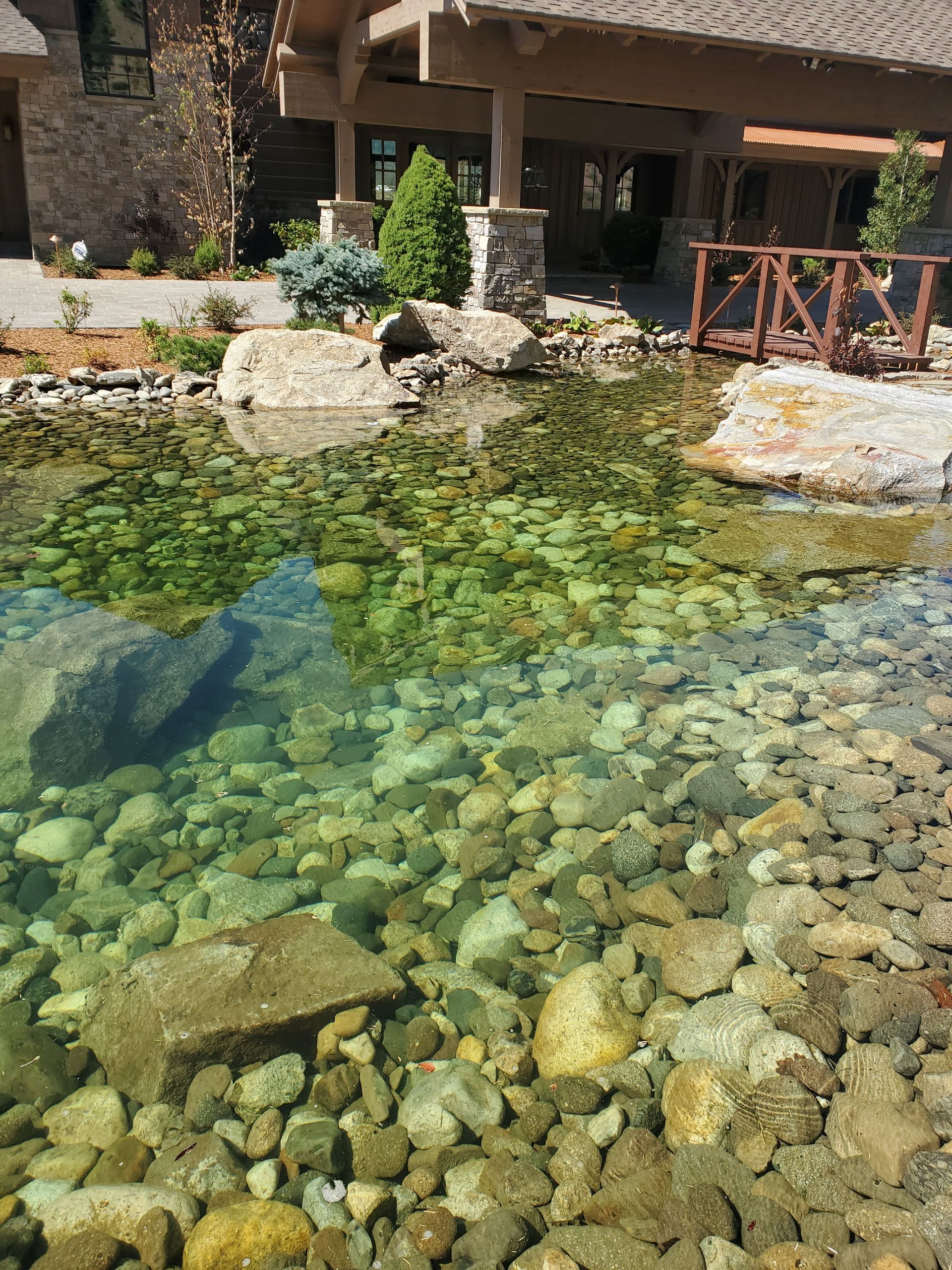 A pond filled with rocks and water in front of a house.