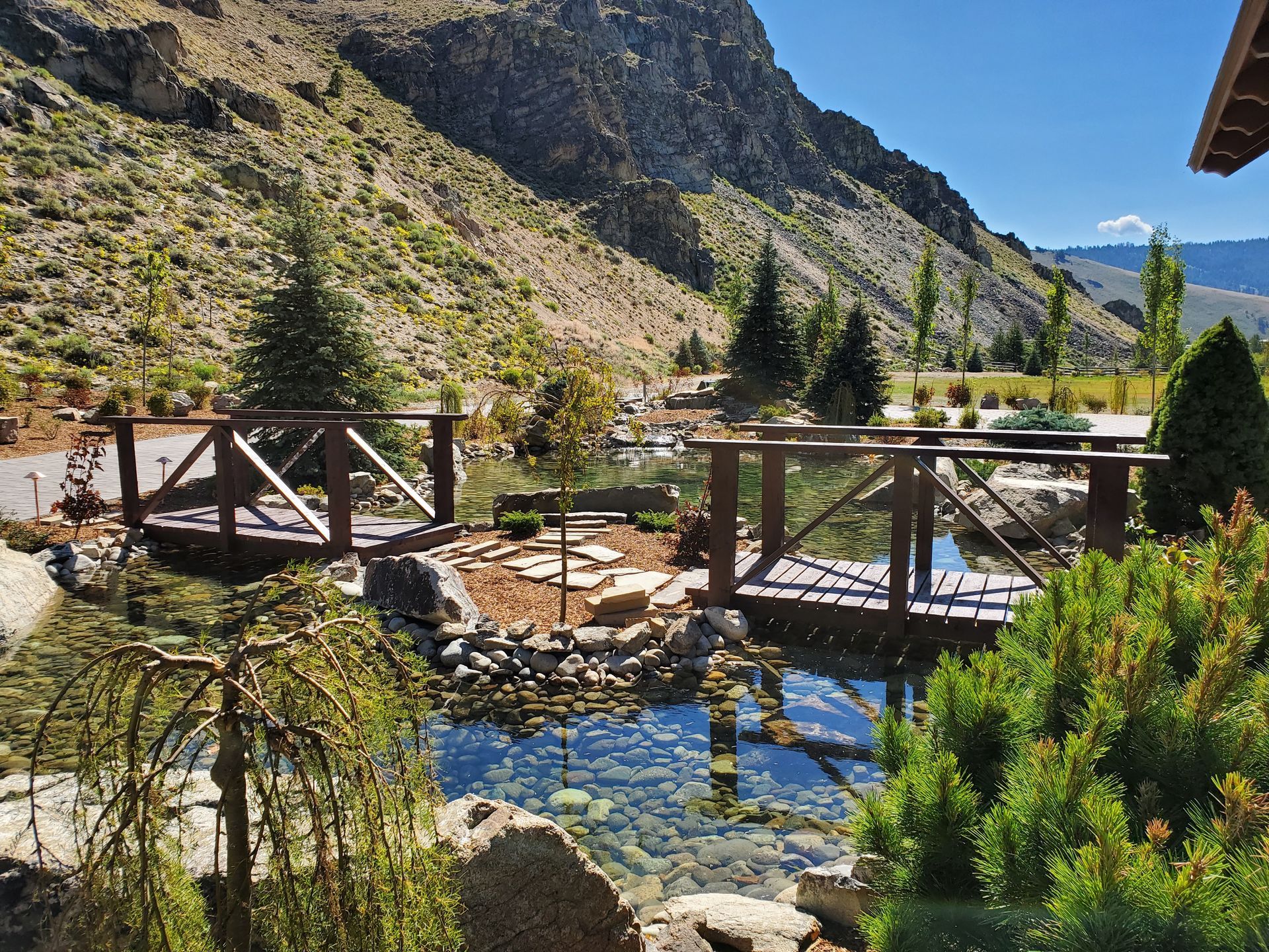 A wooden bridge over a river with mountains in the background