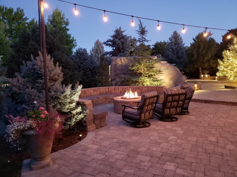 A patio with a fire pit and chairs at night