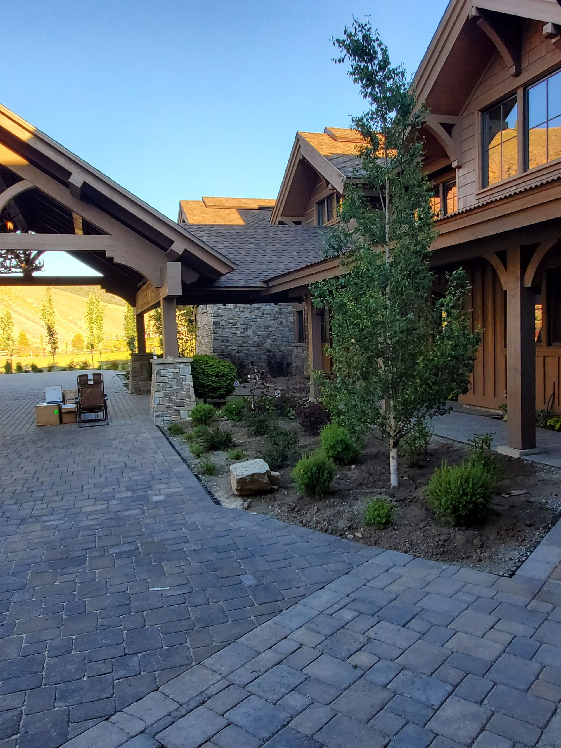 A large wooden house with a brick driveway in front of it.