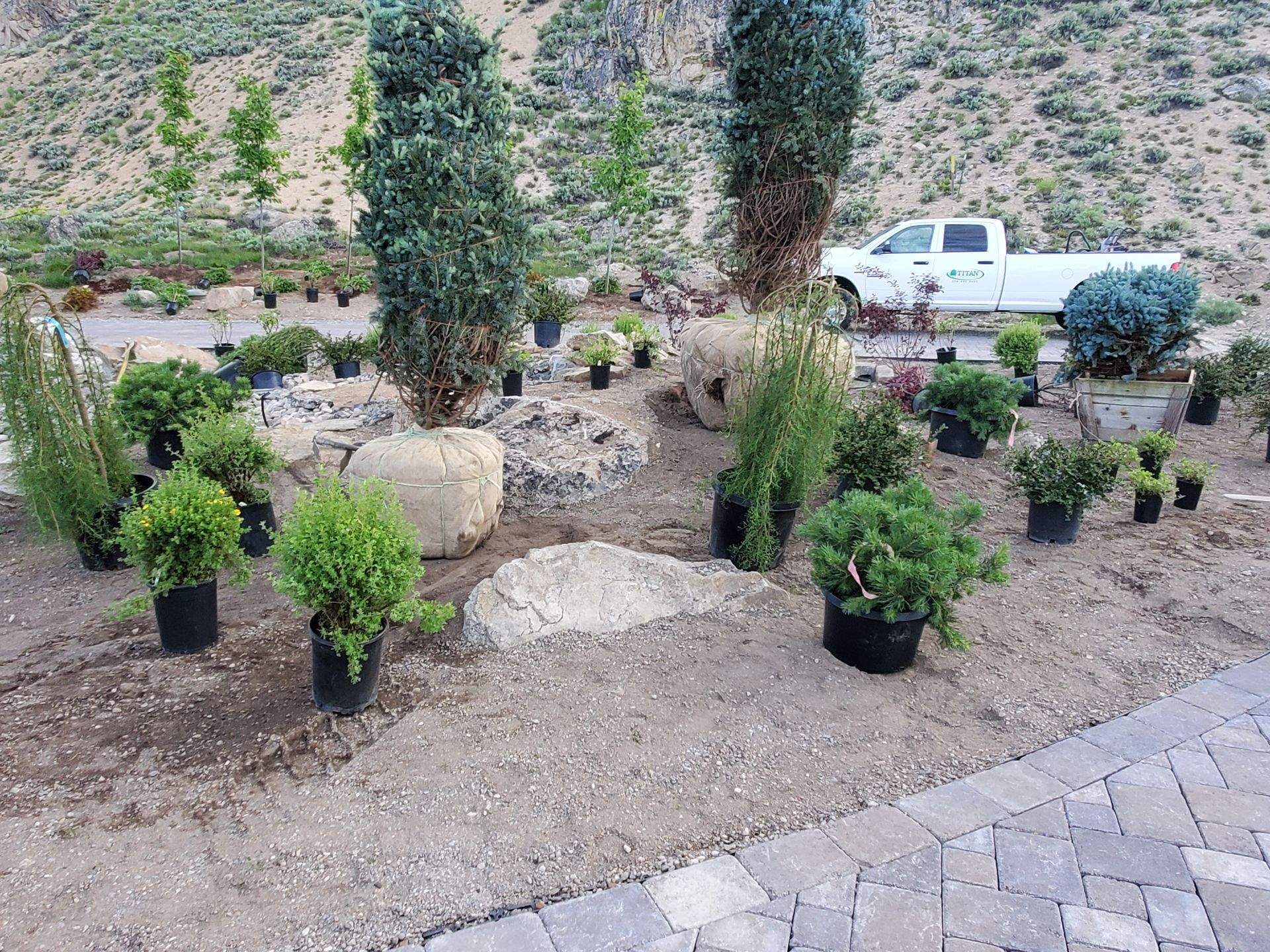 A white truck is parked in a garden filled with potted plants.