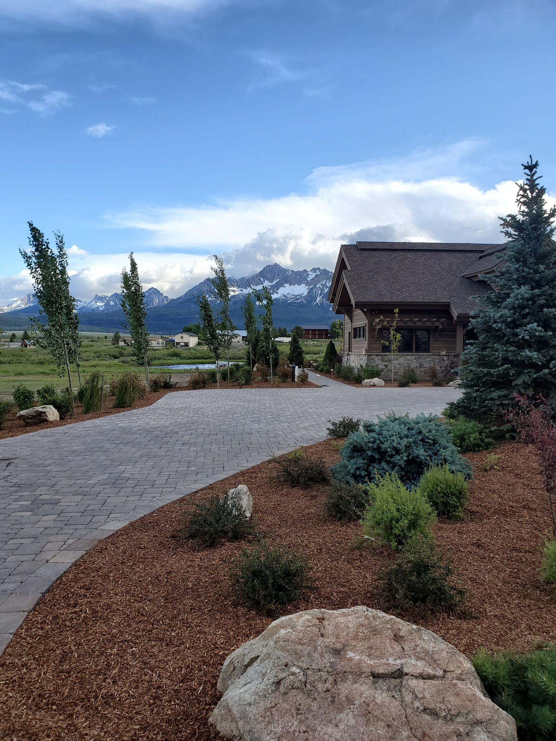 A driveway leading to a house with mountains in the background