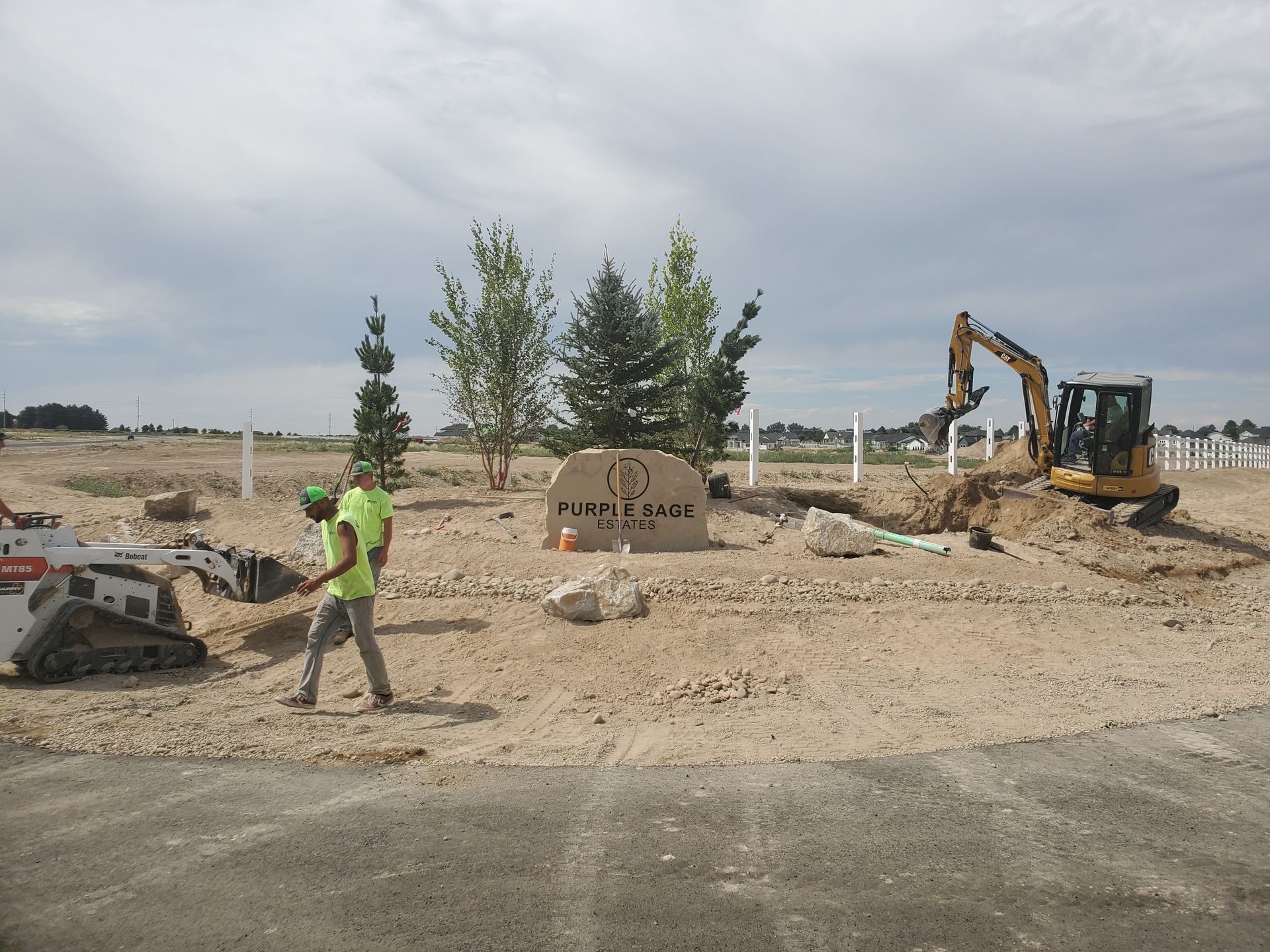 A man in a yellow vest is walking through a dirt field.