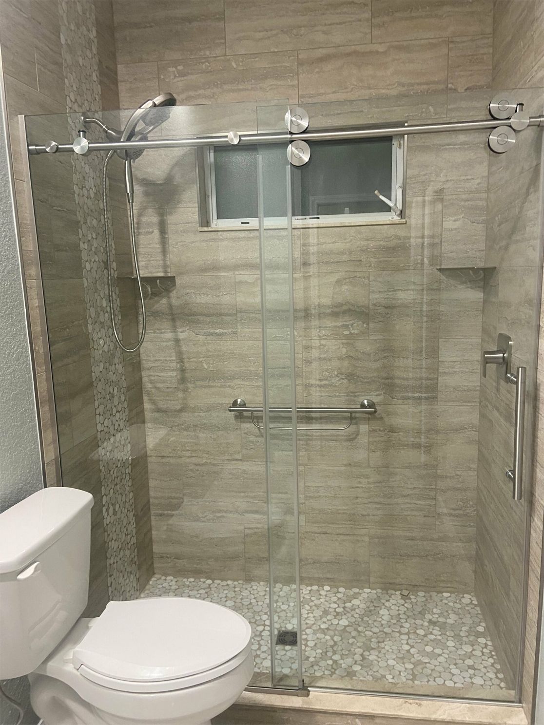 A bathroom with a toilet, shower and sliding glass door
