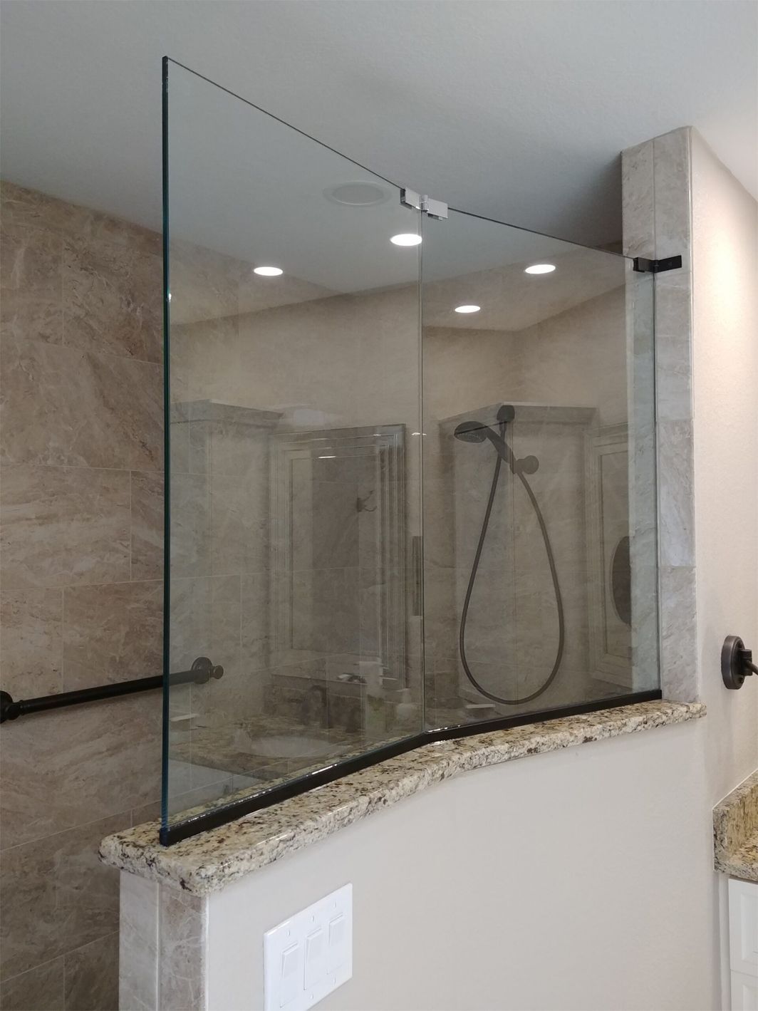 A bathroom with a glass shower door and a shower head