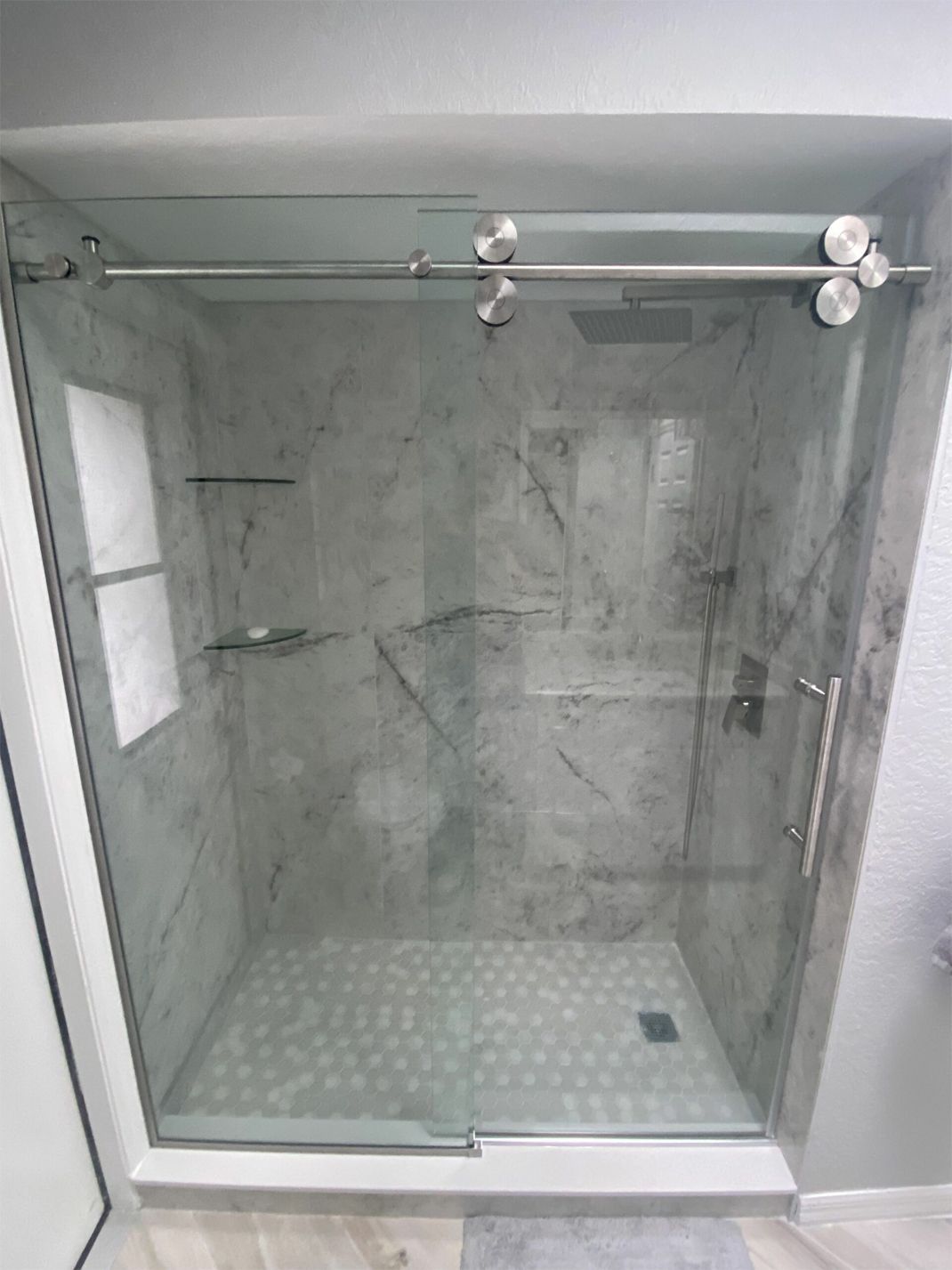 A bathroom with a sliding glass shower door and marble walls