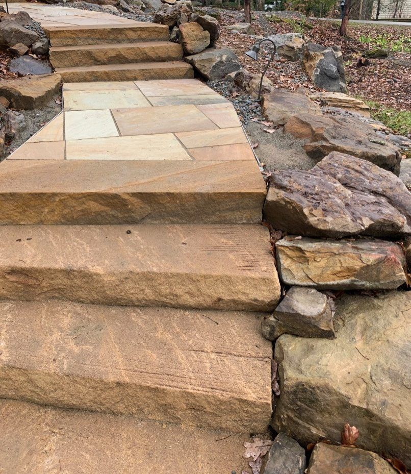 Stone steps and pathway ascending, framed by rock retaining walls, outdoor setting.