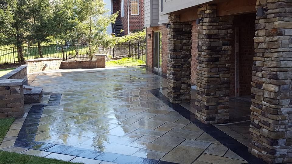 Stone patio with wet surface, brick columns, and surrounding greenery.