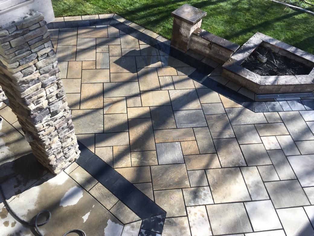 Stone patio with fire pit and pillar, sunny outdoor setting.
