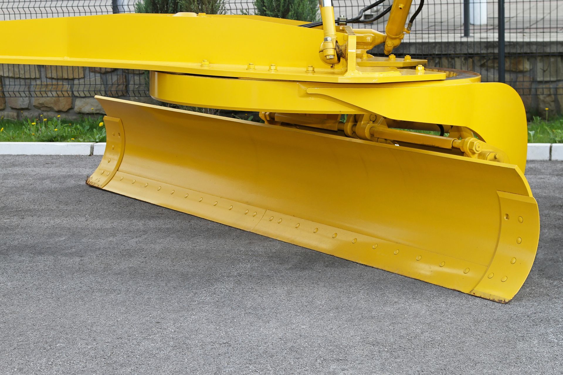yellow road grader blade on asphalt