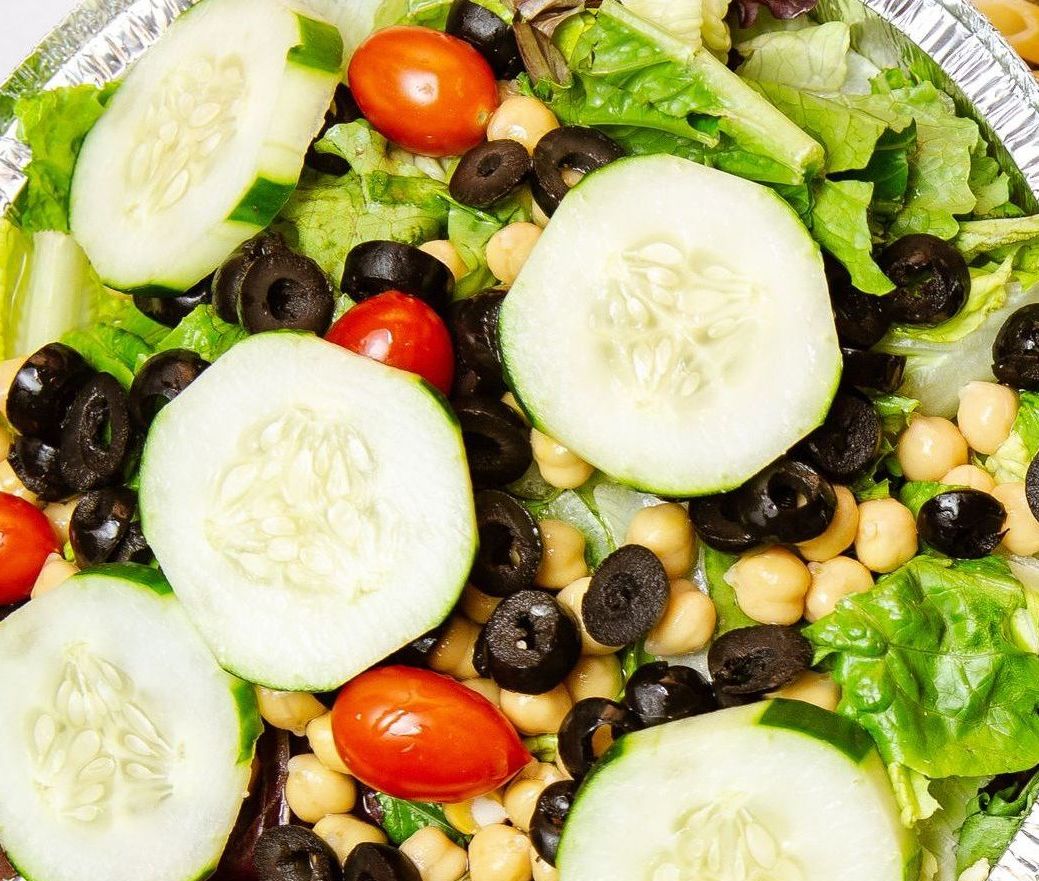 Fresh salad with cucumber slices, black olives, chickpeas, cherry tomatoes, and lettuce