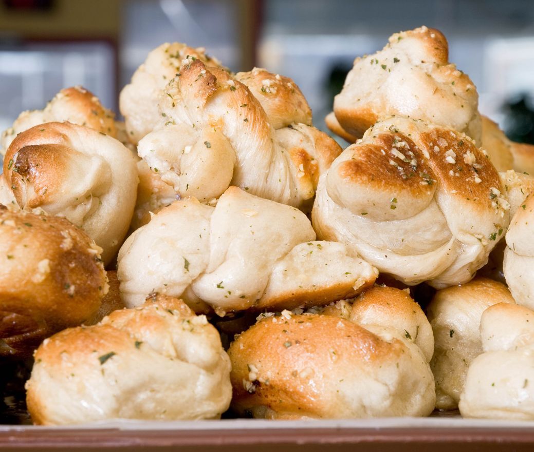 Tray of freshly baked bread rolls topped with sesame seeds and herbs