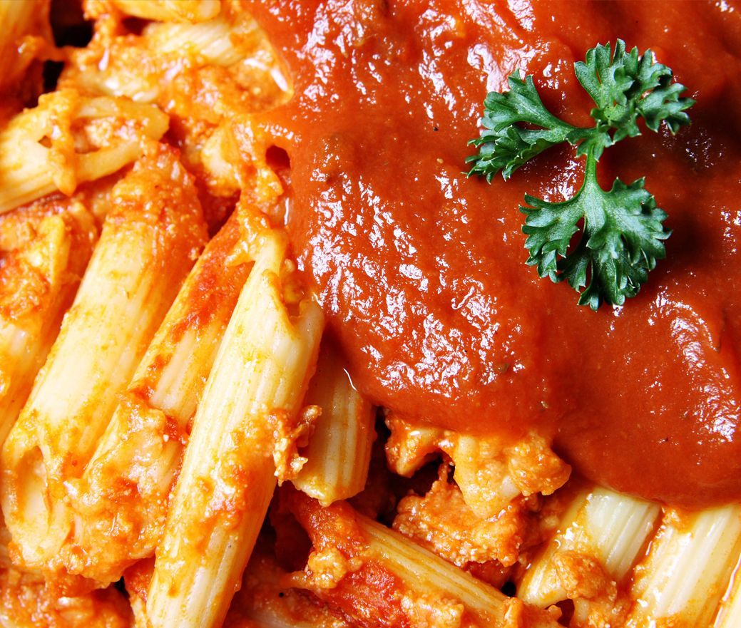 Pasta penne topped with red tomato sauce and a sprig of parsley