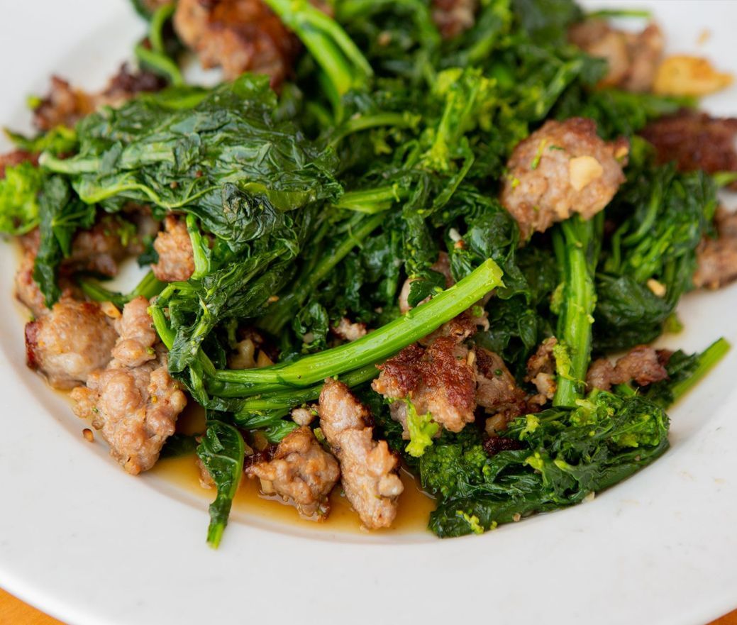 Stir-fried leafy greens with browned meat on a white plate