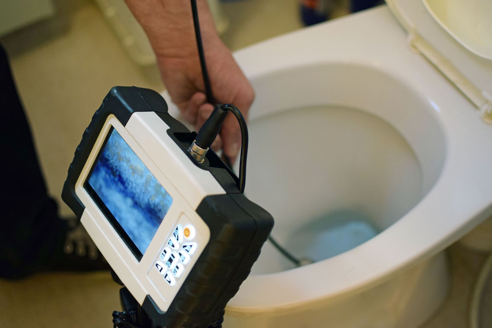 Person using a camera with a screen to inspect the inside of a toilet bowl.