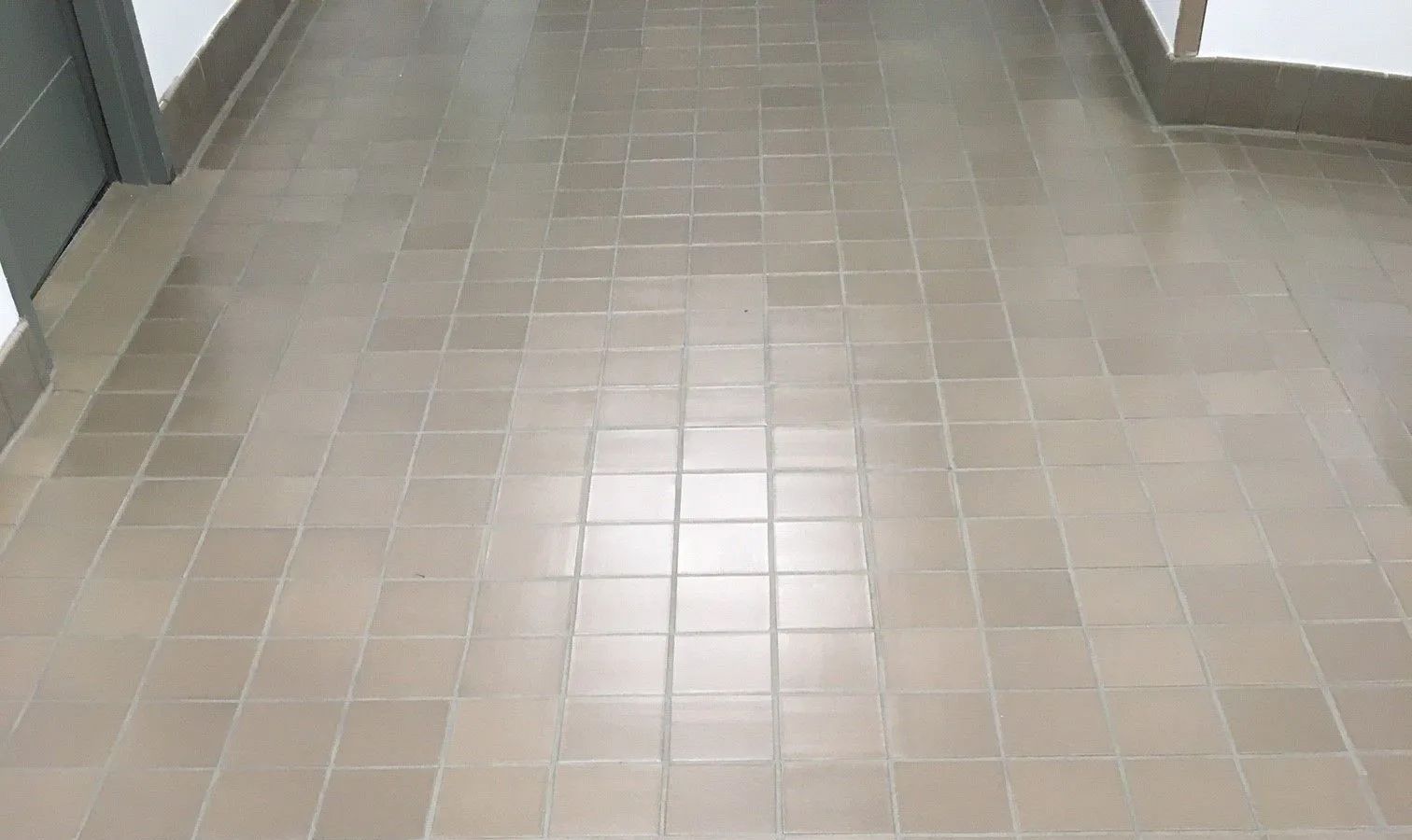A hallway with a tiled floor and a door.