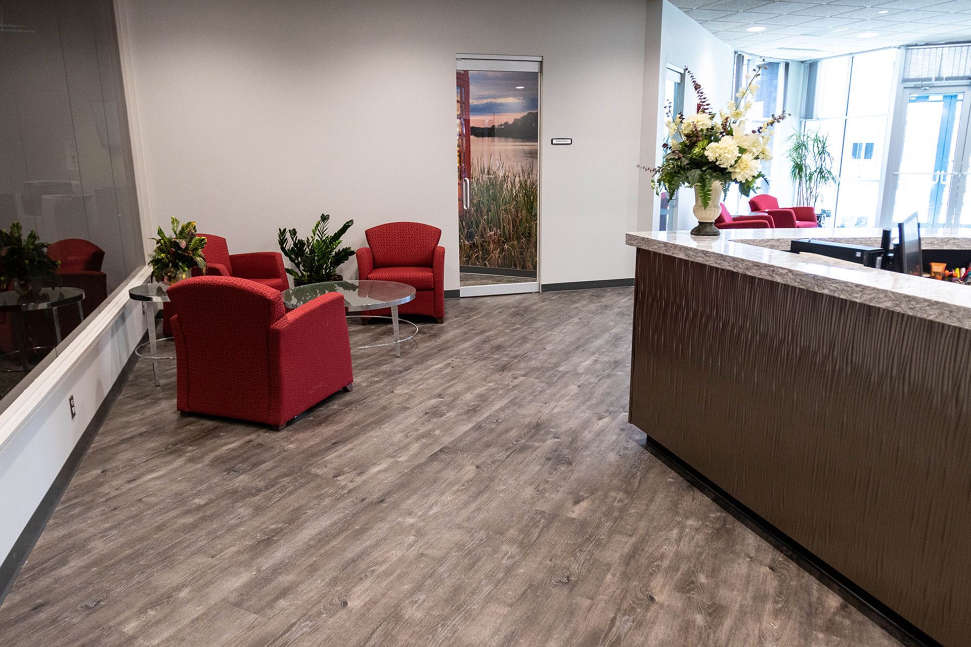 A waiting room with red chairs , a table , and a counter.