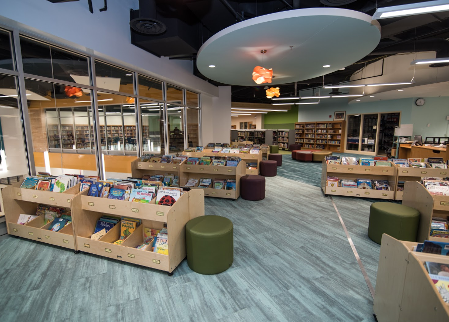 A library with lots of books on shelves and ottomans