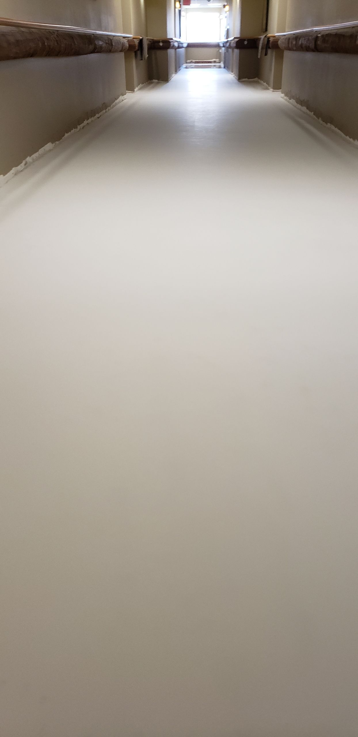 A long hallway with a white floor in a hospital.